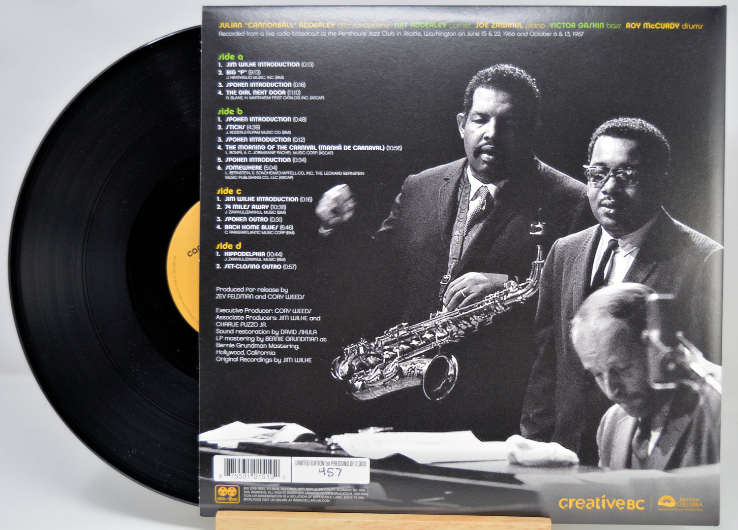 A vinyl record partially pulled from its back cover sleeve, showing the black record and a black-and-white album photo with track listing text. The sleeve features two men in suits and a saxophone, and the record label shows Creative Records branding.