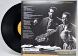 A vinyl record partially pulled from its back cover sleeve, showing the black record and a black-and-white album photo with track listing text. The sleeve features two men in suits and a saxophone, and the record label shows Creative Records branding.