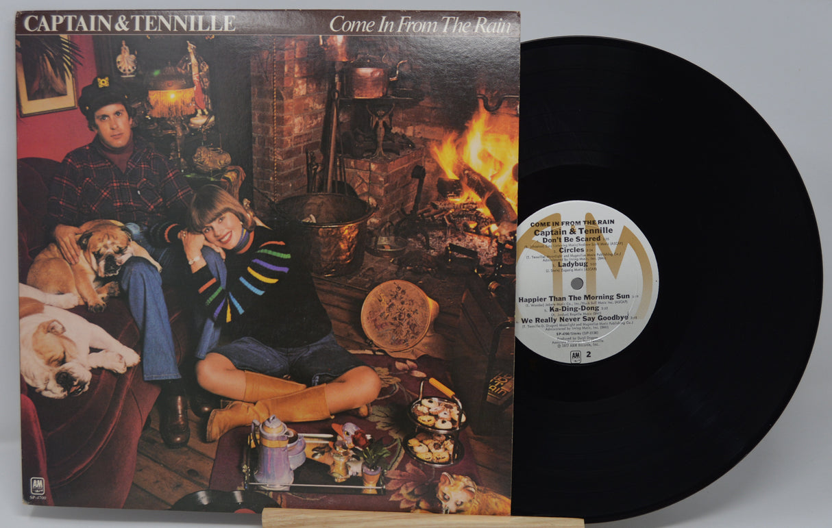 Vinyl record with cover featuring two people and a dog in a cozy room setting.