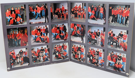 A large gray photo album or collage board displaying multiple printed group photographs of people wearing red tops, photographed on a white surface against a white background.