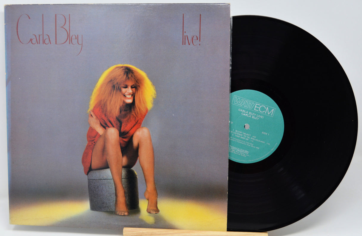 Carla Bley 'live!' vinyl record LP with the printed cover partially pulled from the black record, photographed against a plain light background.