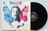 Vinyl record with cover featuring a person and colorful characters on a white background