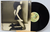 Vinyl record with a cover featuring a woman and a butterfly, on a light gray background.