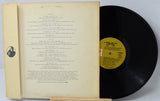 Vinyl record with yellow label and book on a light gray background
