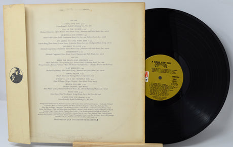 Vinyl record with yellow label and book on a light gray background