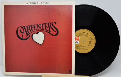 Vinyl record with 'Carpenters' album cover featuring a red background and heart symbol.