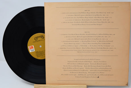 Vinyl record with a yellow label and its cover on a light gray background