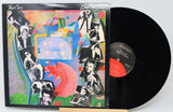 Vinyl record with a colorful cover featuring black and white images of people.