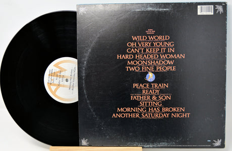 A vinyl record partially pulled from its sleeve, showing the black record and the black album cover with orange and white text listing track titles.