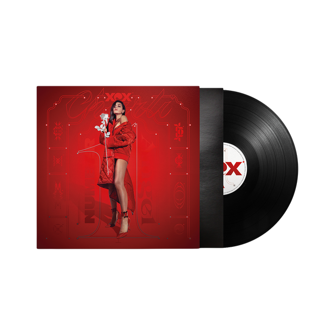 A vinyl record partially pulled from its sleeve, shown on a plain white background. The album cover is predominantly red with a stylized portrait of a woman in a red outfit, and the black record has a red-and-white center label.