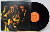 Cheap Trick 'at Budokan' vinyl record album with the printed cover sleeve in front and the black LP record partially pulled out, showing the orange center label.