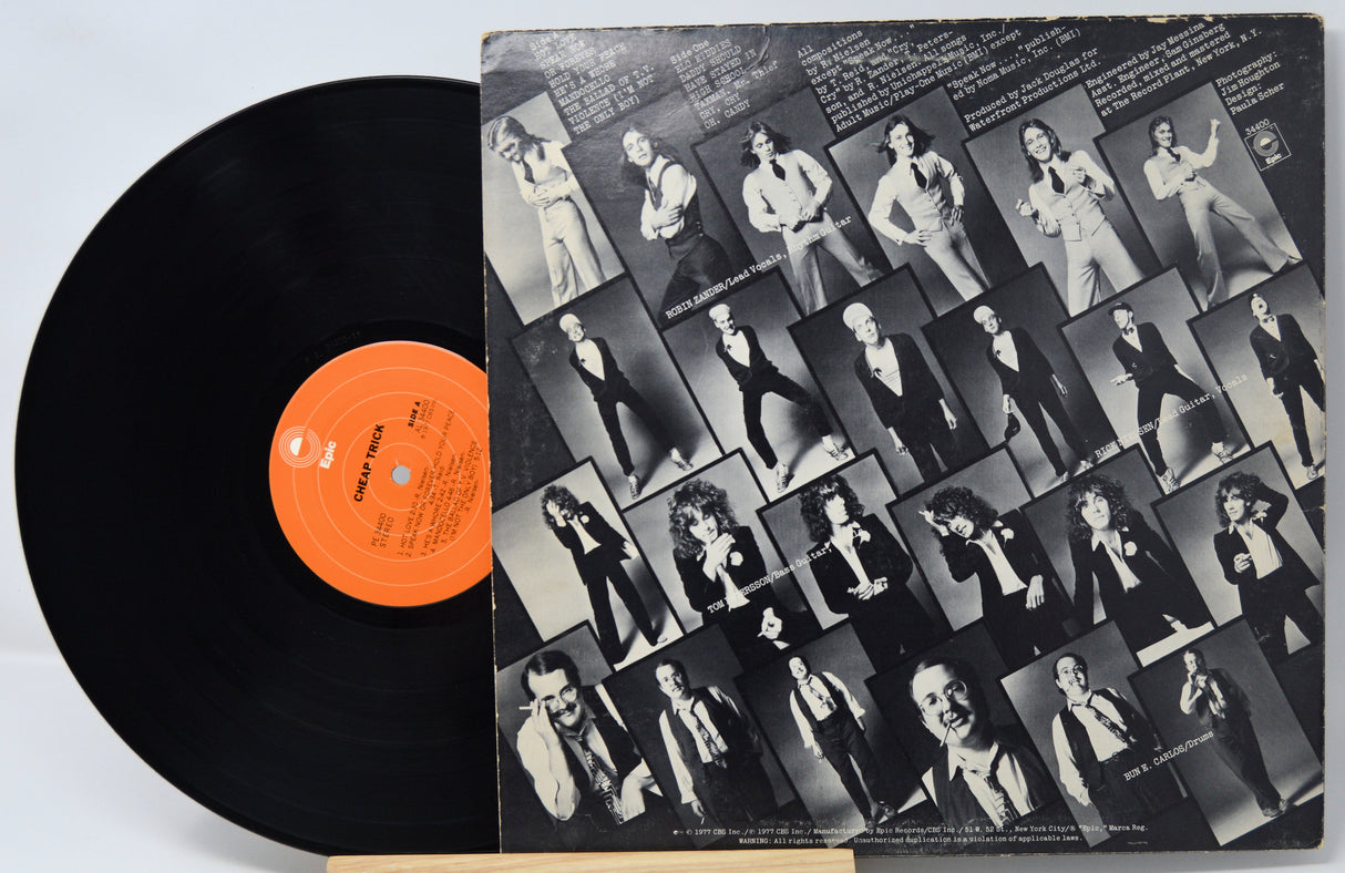 Vinyl record with a black cover featuring multiple images of a person, on a light gray background.