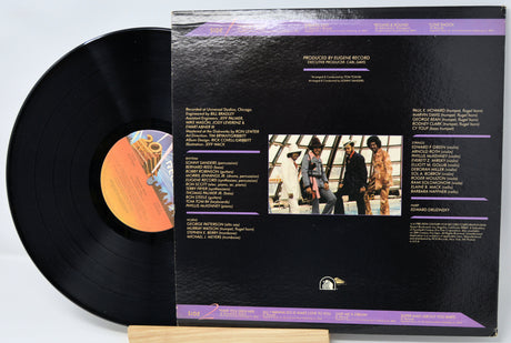 Vinyl record with its cover displaying text and images on a light gray background