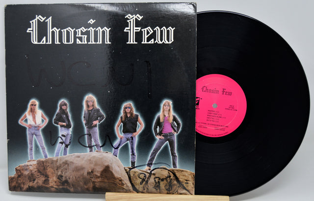 Vinyl record with cover featuring a band on a rock, on a light gray background