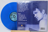 Blue vinyl record with a music album cover featuring a portrait and tracklist.