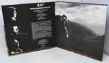 Album cover with black and white images of a musician and text on a mountainous landscape.