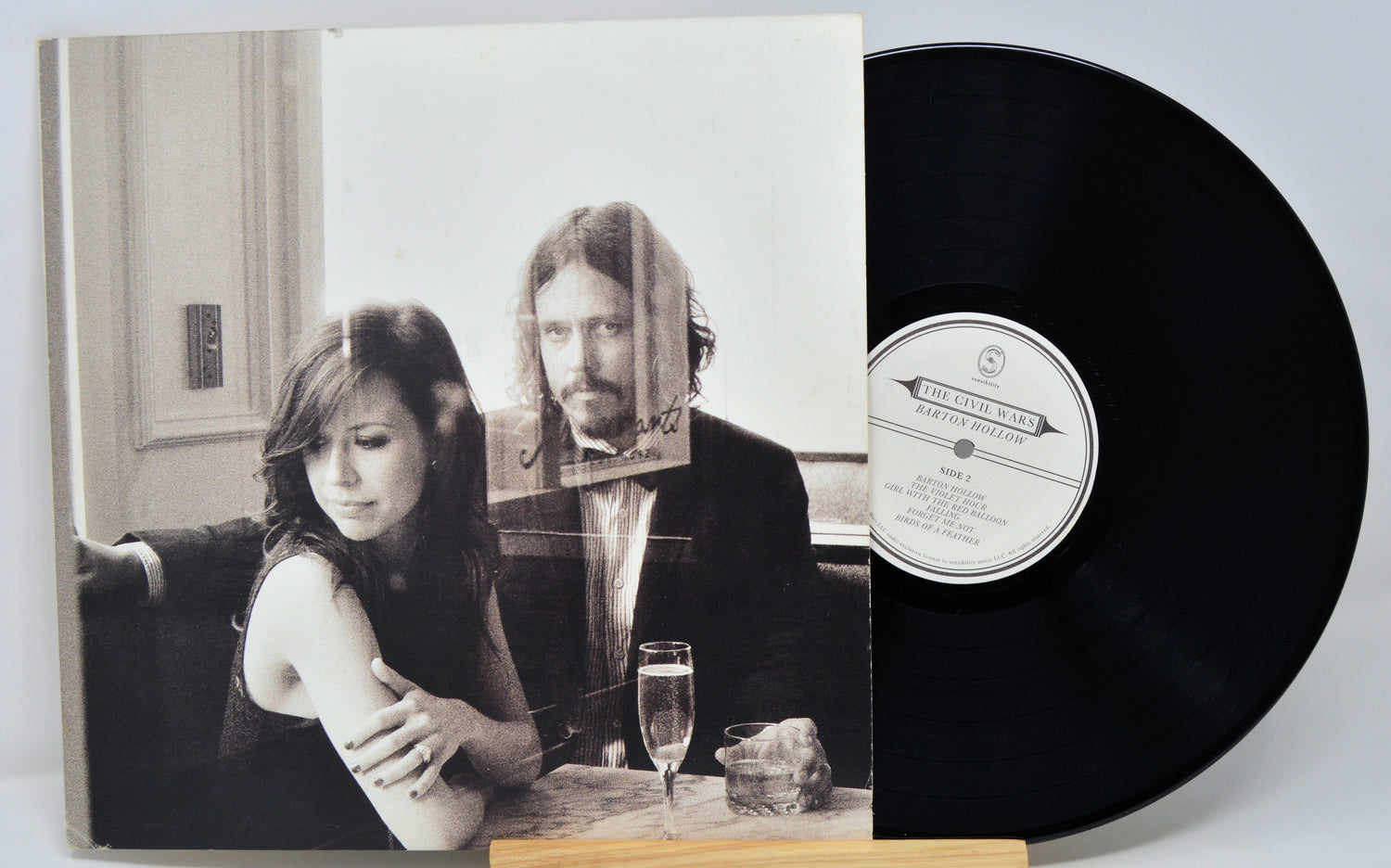 Vinyl record with a black and white cover featuring two people at a table.