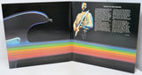 Album cover with a rainbow stripe and a person holding a guitar.