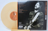Vinyl record with a cover featuring Eric Clapton playing guitar, on a light blue background.