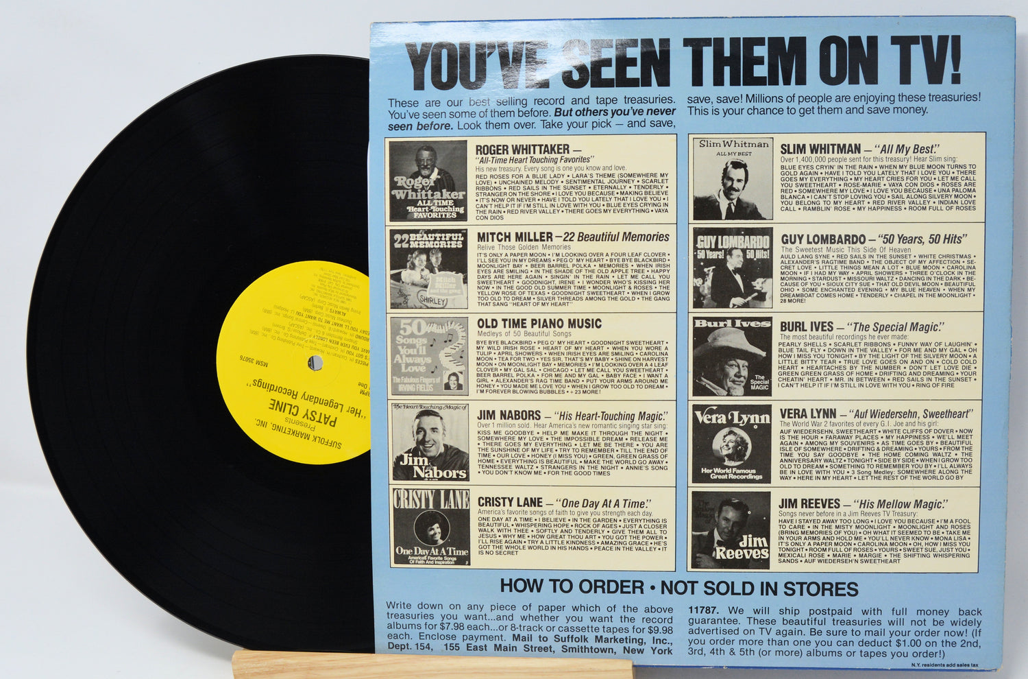 Vinyl record with a colorful sleeve featuring text and images of people, on a light gray background.