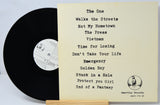 Vinyl record with a list of song titles on a stand against a light background