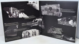 Open book with black and white photographs and text on a white surface