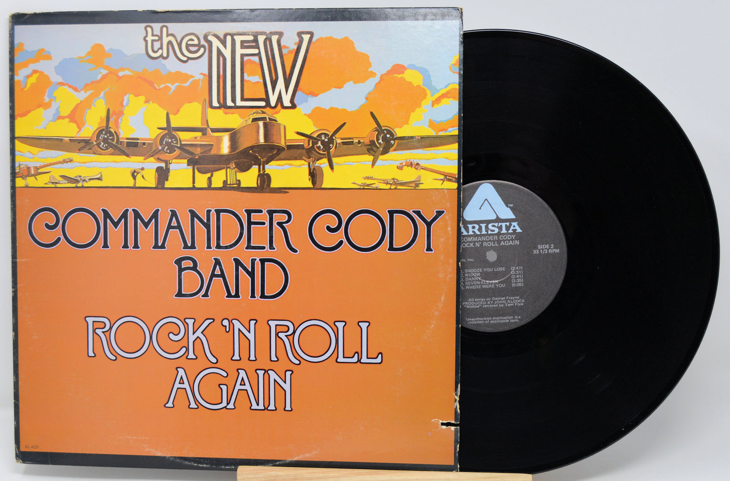 Vinyl record with 'The New Commander Cody Band Rock 'N Roll Again' album cover featuring an airplane illustration.