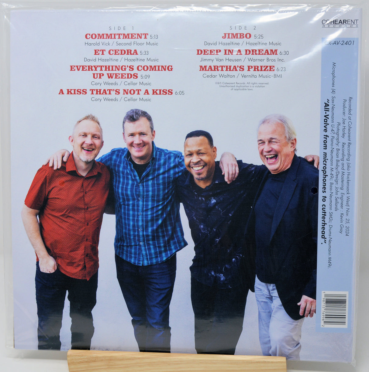 A square album cover for 'Side by Side' by four comedians, sealed in a clear plastic sleeve. The cover features a white background with red and black text, and a group photo of the four men smiling and laughing.