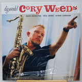 A vinyl record sleeve for Cory Weed's 'dig weedz!' album, featuring a photo of the saxophonist pointing while holding a saxophone. The sleeve is wrapped in clear plastic, and the Coherent Records logo is visible in the bottom right corner.