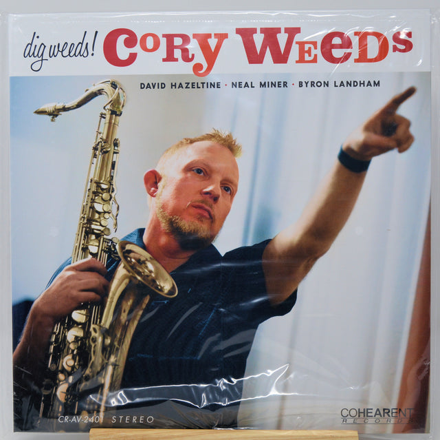 A vinyl record sleeve for Cory Weed's 'dig weedz!' album, featuring a photo of the saxophonist pointing while holding a saxophone. The sleeve is wrapped in clear plastic, and the Coherent Records logo is visible in the bottom right corner.