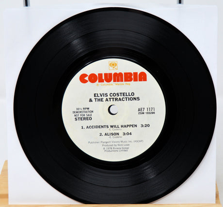 Vinyl record with a colorful cover featuring people dancing and playing drums, on a light gray background.