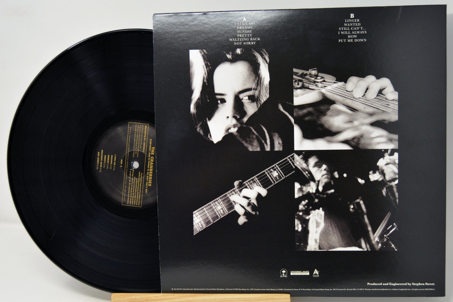 A vinyl record partially pulled from its black outer jacket, showing the back cover artwork with black-and-white photos of a musician playing guitar and text for Bob Dylan's album 'The Power and the Glory'.