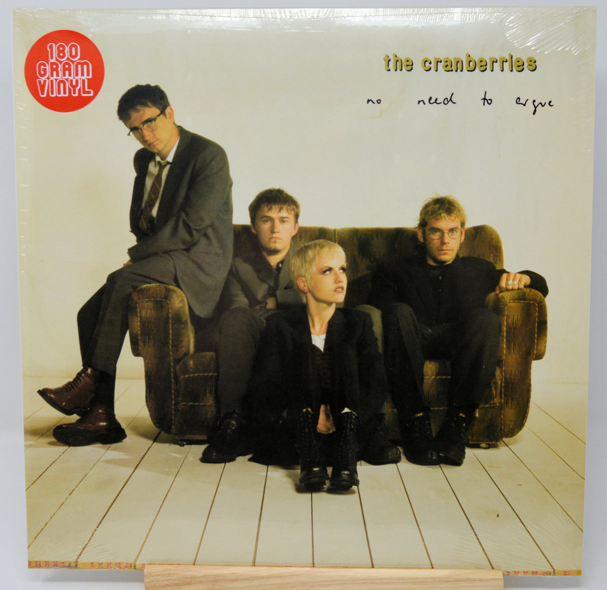 The Cranberries 'No Need to Cry' 120 gram vinyl record LP in its original shrink wrap, displayed on a wooden stand against a white background.