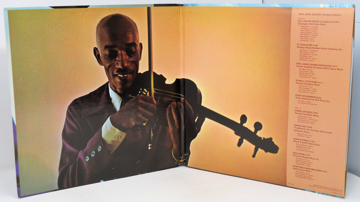 Vinyl record cover with a person playing a stringed instrument on the left side and text on the right.