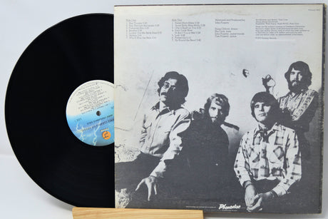 Vinyl record with a black cover featuring a group of people and a white label.
