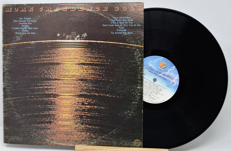 Vinyl record with cover featuring a sunset over water scene