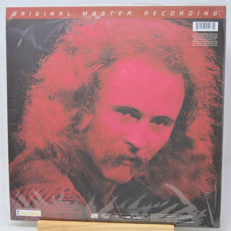 Vinyl record album cover for 'Original Master Recording' featuring a stylized portrait of a man with long hair in red and black tones, photographed in shrink wrap on a light surface.