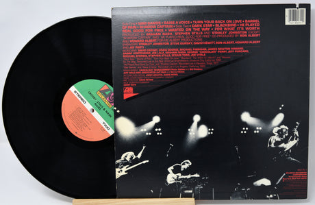 Vinyl record with cover featuring a black and white image of a concert and red text.