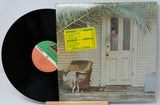 Vinyl record with a colorful label and cover featuring a house and chair.