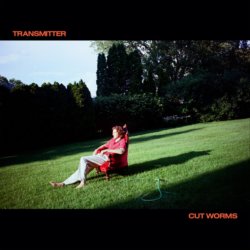 Person sitting on a red chair in a grassy field with trees in the background, album cover for 'Transmitter' by Cut Worms.