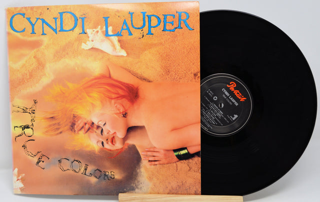 Cyndi Lauper album 'True Colors' with a portrait of the artist on the cover, placed on a wooden surface.