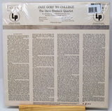 The back cover of a LP vinyl record for 'Jazz Goes to College' by The Dave Brubeck Quartet, wrapped in protective plastic and resting on a wooden display stand.