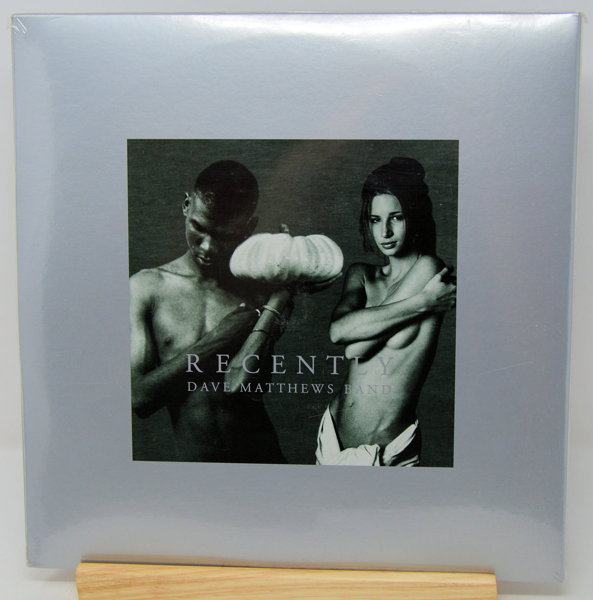 Dave Matthews Band 'Recently' vinyl record album cover, sealed in plastic shrink wrap and displayed on a wooden stand against a light gray background.