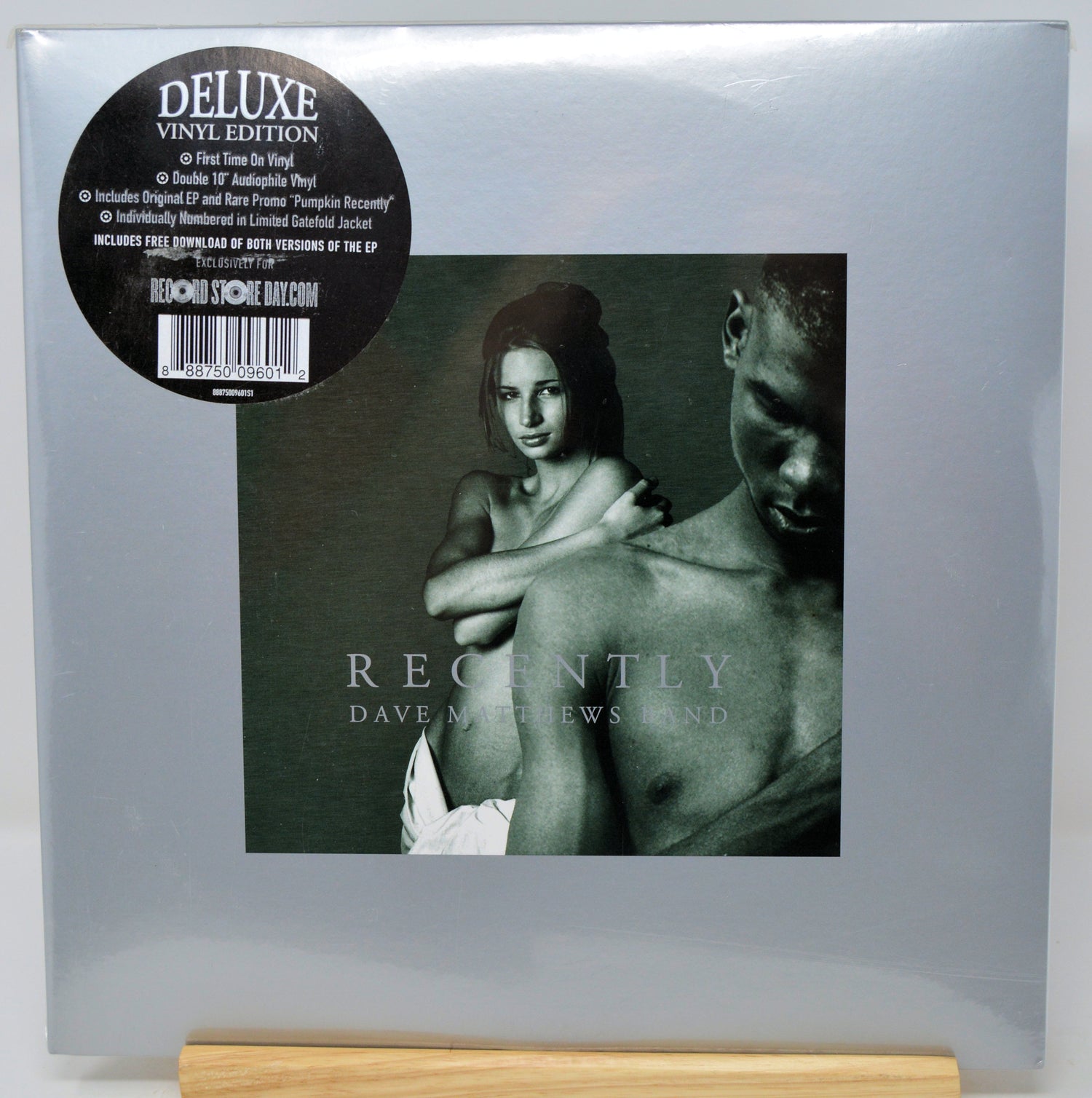 Dave Matthews and Linda 'Recently' Deluxe Vinyl Edition LP cover, sealed in its original plastic shrink wrap and standing on a light wood block. The cover is a muted gray-green with a black circular sticker on the top left.