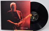 David Gilmour 'The Memories of Ballad' vinyl record LP with its illustrated cover sleeve and a partially visible black vinyl record on a stand.