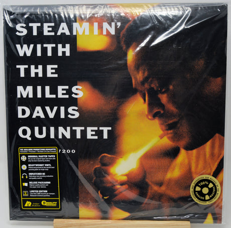 Steamin' With the Miles Davis Quintet vinyl record album in its original shrink wrap, displayed on a wooden stand. The cover art features a dramatic portrait of Miles Davis with a match, rendered in fiery orange and yellow tones against a black background, with white title text and a yellow 'Limited Edition' seal.