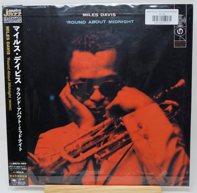 Miles Davis 'Round About Midnight' vinyl record cover, Japanese edition, with a red-tinted photo of the artist playing trumpet and Japanese text on the left side. The record is sealed in plastic shrink wrap.
