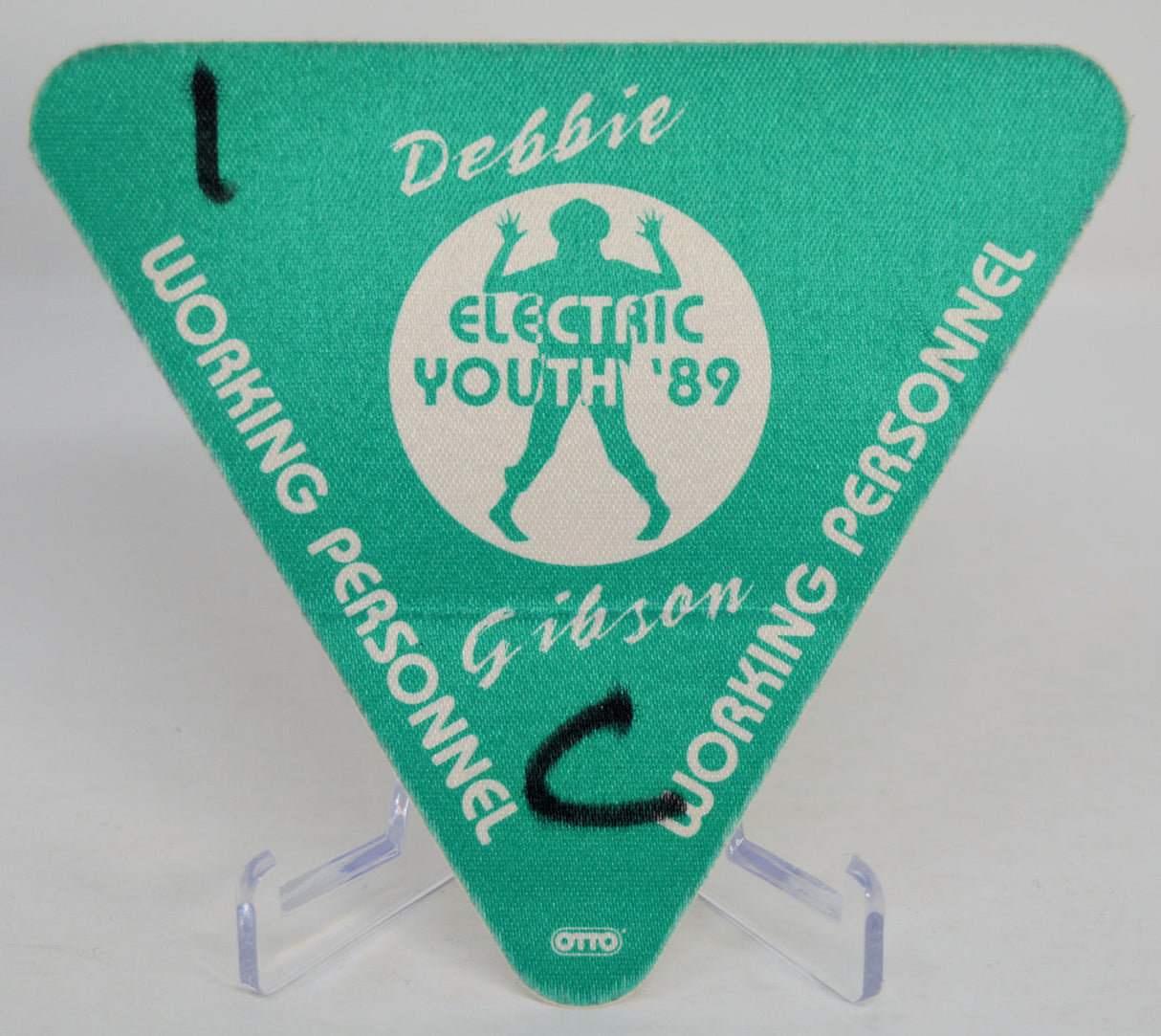 Green triangle-shaped backstage pass with 'Debbie Gibson Electric Youth '89' design on a clear stand.