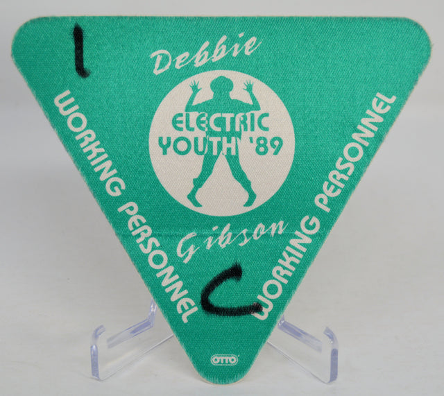 Green triangle-shaped backstage pass with 'Debbie Gibson Electric Youth '89' design on a clear stand.