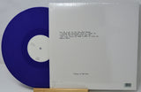 Blue vinyl record with white label and white sleeve on a gray background